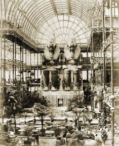 an old photo of the inside of a building with statues and plants on display in it