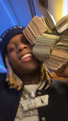 a person holding stacks of money in front of their face and smiling at the camera