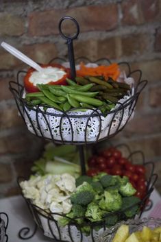 three tiered trays filled with different types of vegetables and fruit on top of each other