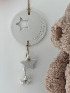 a teddy bear is next to a hanging star ornament on a white wall