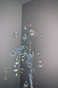 soap bubbles are floating in the air next to a water faucet and wall