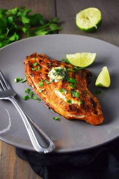 a piece of fish is sitting on a plate with limes and cilantro