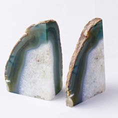 two pieces of green and white marble sitting next to each other on a white surface