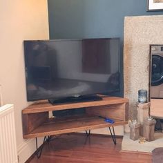 a flat screen tv sitting on top of a wooden stand next to a dryer