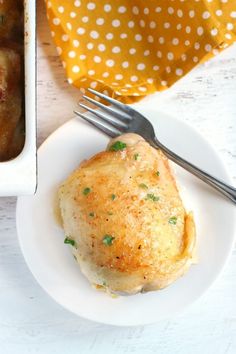 a white plate topped with food next to a pan filled with meat covered in gravy