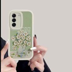 a woman is holding up her phone case with flowers on the front and bottom cover