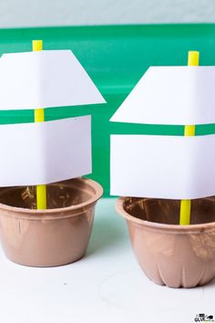 two cups with paper boats on them sitting next to each other