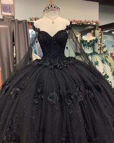 Step into your Quinceanera with elegance and mystery in this stunning black ball gown. This dress is crafted from luxurious tulle and features a dramatic ball gown silhouette with a chapel train that adds a royal finish to your look. The sweetheart neckline and long sleeves exude sophistication, while the intricate beading and appliqued floral details bring a soft yet bold charm to the ensemble. A corset back ensures a perfectly sculpted fit, making this dress as comfortable as it is enchanting. Black And Pink Quinceanera Theme, Emo Quinceanera, Black Quince Theme, Quinceanera Dresses With Flowers, Black Ball Gown Dress, Black Quince Dress, Long Sweet 16 Dresses, Lavender Prom Dress Long, Butterfly Quince