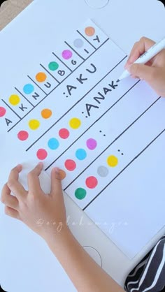 a person is writing on a paper with colored dots