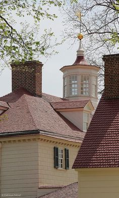 two white houses with red roof tops next to each other in front of some trees