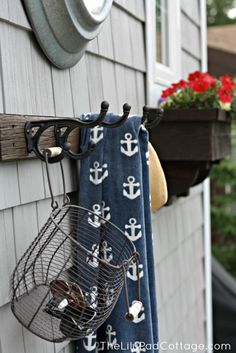 a towel hanging on the side of a house next to a birdcage and potted plant