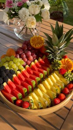 a bowl filled with lots of different types of fruit on top of a wooden table