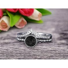 a black diamond ring sitting on top of a wooden table next to pink tulips