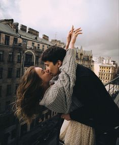 a man and woman kissing on top of a building