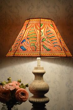 a lamp that is on top of a table next to a vase with flowers in it