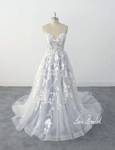 a white wedding dress on a mannequin with floral appliques and sheer tulle