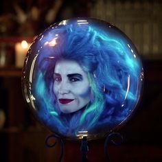 a close up of a person with blue hair in a glass ball on a stand