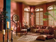 a living room filled with lots of furniture next to tall windows covered in lattices