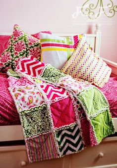 a bed with pink, green and white pillows on it next to a wall decal