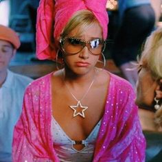 a woman wearing sunglasses and a star necklace in front of other people sitting at a table