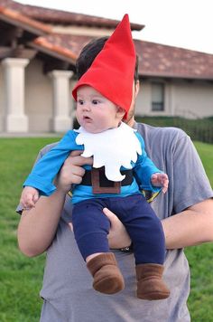 a man holding a baby wearing a gnome costume