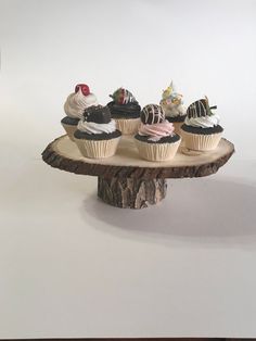 four cupcakes sitting on top of a tree stump in front of a white background