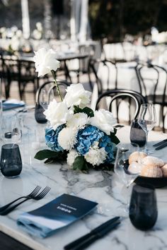 the table is set with blue and white flowers, silverware, and napkins