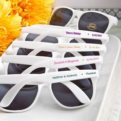 six pairs of white sunglasses sitting on top of a table next to yellow carnations