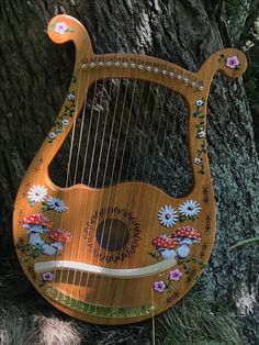 an old wooden harp sitting on the ground next to a tree with flowers painted on it