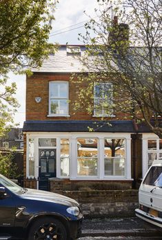 two cars parked in front of a brick house