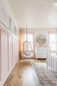 a bedroom with pink walls and wooden floors, white bedding and hanging hammock chair