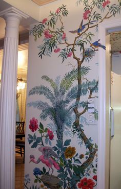 the wall is painted with birds and flowers on it, along with white pillars that lead into an entry way