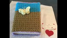 a crocheted book with a butterfly on it and a card holder next to it