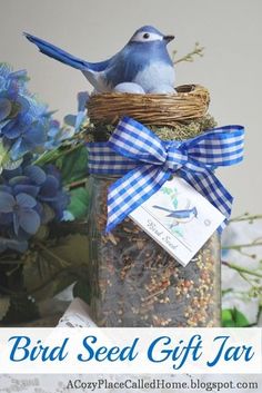 a blue bird sitting on top of a jar filled with birdseed next to flowers