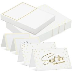 four white cards with gold foil lettering and polka dots on the front, two are folded in