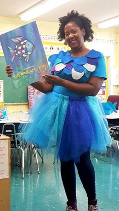 a woman in a blue dress is holding a book