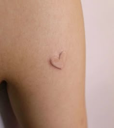 a small heart tattoo on the back of a woman's thigh