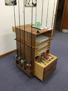 a wooden cabinet with fishing rods hanging from it's sides and two drawers on the bottom