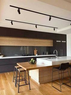 a kitchen with an island, sink and bar stools in front of the counter