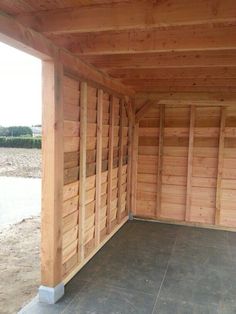 the inside of a building with wooden walls and doors on both sides, in front of a parking lot