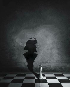 the shadow of a person standing in front of a chess board