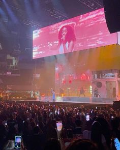 a large group of people at a concert with cell phones in front of the stage