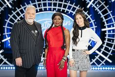 three people standing next to each other in front of a stage with an american idol on it