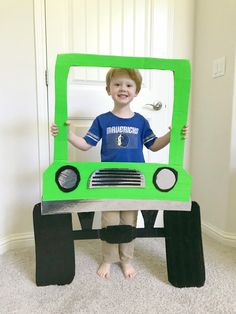 a young boy standing in front of a green truck costume