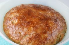 a baked bread in a white bowl on a blue cloth