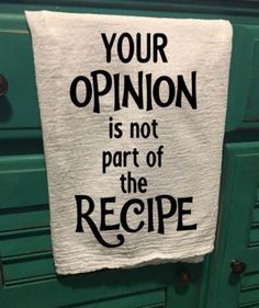 a tea towel hanging on the side of a green cabinet that says your opinion is not part of the recipe