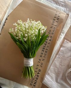 a bouquet of white flowers sitting on top of a piece of paper next to a brown envelope