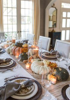 a dining room table is set with pumpkins and candles