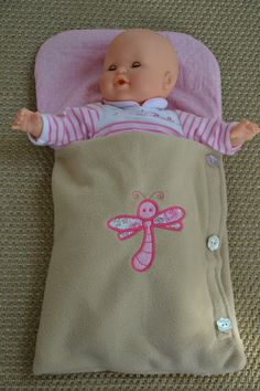 a baby doll laying on top of a blanket