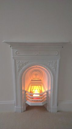 a white fireplace with a lit fire in it's mantle and carpet on the floor